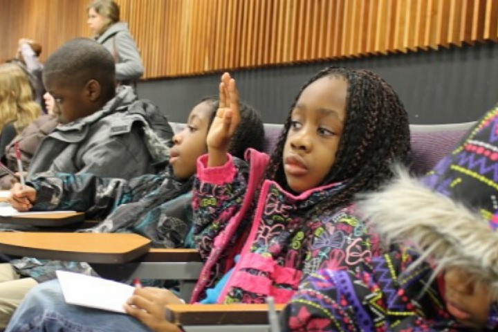Young people taking notes at a MCYU Family Lecture. A girl raises her hand.